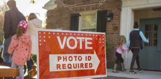Red voting sign with arrow near people entering a polling place