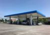 Gas station canopy with fuel pumps and vehicles on a clear day