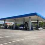 Gas station canopy with fuel pumps and vehicles on a clear day
