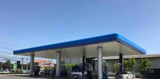 Gas station canopy with fuel pumps and vehicles on a clear day