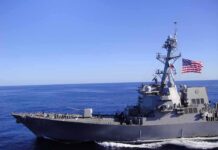 U.S. Gunfire: Maritime Standoff Escalates Naval destroyer sailing on open sea with flag flying