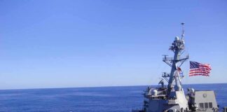 Naval destroyer sailing on open sea with flag flying