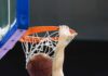 Basketball player dunks ball through orange rim