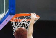 Basketball player dunks ball through orange rim