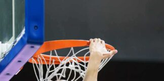 Basketball player dunks ball through orange rim