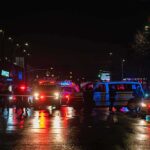 Nighttime police scene with flashing lights on a wet city street