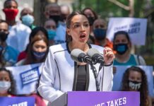 Woman speaking at outdoor rally behind microphones