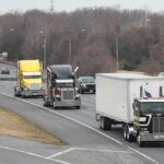 Convoy of semi trucks driving on a multi-lane highway