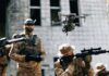 Quadcopter drone flying above soldiers in camouflage