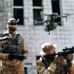 Quadcopter drone flying above soldiers in camouflage