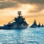 Naval warships anchored in a harbor at sunset