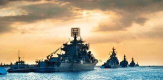 Naval warships anchored in a harbor at sunset
