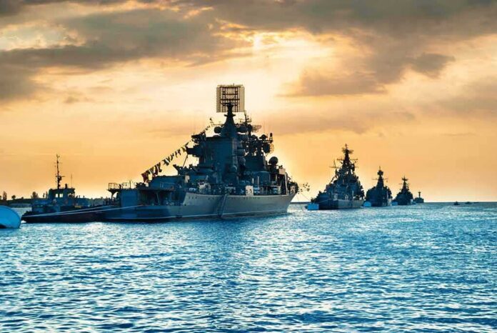 Naval warships anchored in a harbor at sunset
