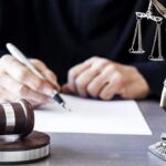 Court Ruling Draws New Line on AI-Generated Child Abuse Images Judge writing at desk with gavel and Lady Justice statue
