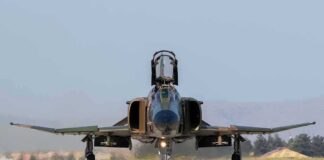 Military jet taxiing on runway with open canopy