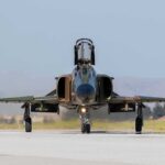 Military jet taxiing on runway with open canopy