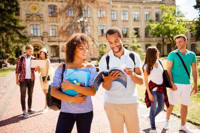 shutterstock_684325948 Students walking on campus with books and backpacks