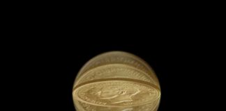 Gold coin distorted through a crystal ball on black background
