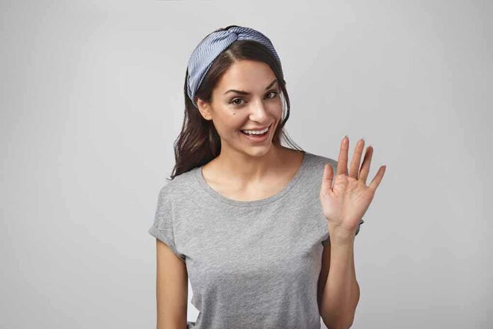 shutterstock_1094752205 woman smiling and waving in a gray t-shirt