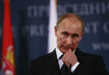 Putin Ally Bankrolls: Russian-Funded Bahamas Bash man in suit at podium touching his face