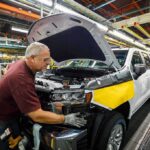factory worker assembling a pickup truck on an automotive production line