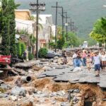 Residents walk along a heavily damaged street after a disaster