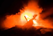 Toy helicopter silhouette against fiery explosion at night