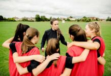 WNBA Trans Debate Intensifies Coach talks to youth team in a huddle on a field