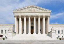 Justice’s Stock Holdings Spark Ethics Debate Front view of the Supreme Court building with large columns and steps under a blue sky