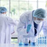 Scientist pipetting blue liquid into test tubes in a laboratory