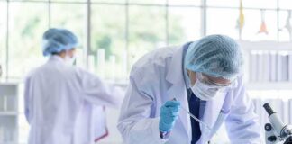 Scientist pipetting blue liquid into test tubes in a laboratory