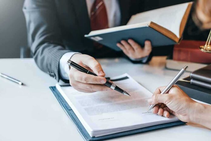 shutterstock_1414855505-1 Hands signing a legal document at a desk