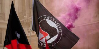 protesters with antifascist flags and purple smoke