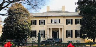 Holiday wreaths on iron gate before a grand mansion