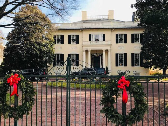 shutterstock_1617597283 Holiday wreaths on iron gate before a grand mansion