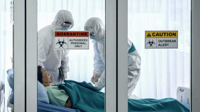 shutterstock_1647350797 Healthcare workers in hazmat suits treat a patient in a quarantine room