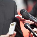 Music Kingpin Gone — Era Ends microphones held toward a person in a suit