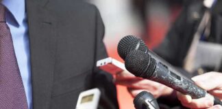microphones held toward a person in a suit