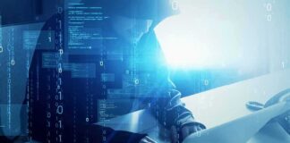 Hooded figure using a laptop with digital code overlay