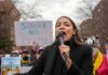 AOC’s Role Becomes Democratic Campaign Issue woman speaking into a microphone at an outdoor protest