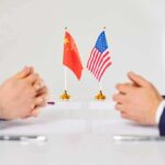 Middle East Chaos: Qatar’s Power Play Exposed Two diplomats sit across table with China and United States flags between them
