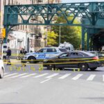 Police cars block a city intersection with yellow crime scene tape