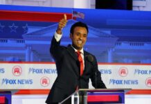 Fox News Adds Former Cuomo Aide as Contributor smiling man in suit at debate podium giving thumbs up