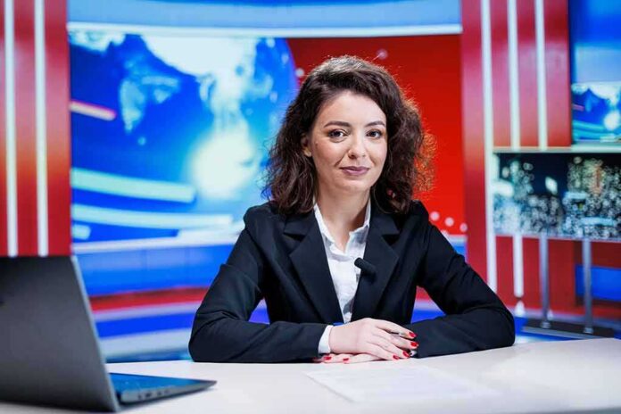shutterstock_2550477051-1 News anchor seated at a broadcast desk