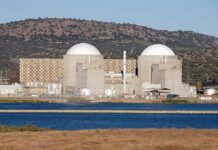 China’s Reactor: A Nuclear Buildout Surges Nuclear power plant with domed structures beside a water body and mountains in the background