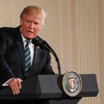 Donald Trump speaking at a podium with presidential seal