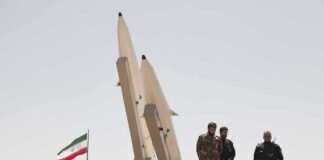 Soldiers stand beside large missiles at an outdoor display