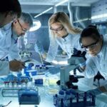 Rebooting Dead Brains, Live Tests — Pharma Shook Scientists collaborating in a laboratory around a microscope