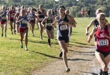 women cross-country runners racing on a grassy trail