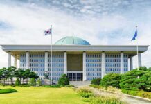 Parliament building with a green dome and flagpoles
